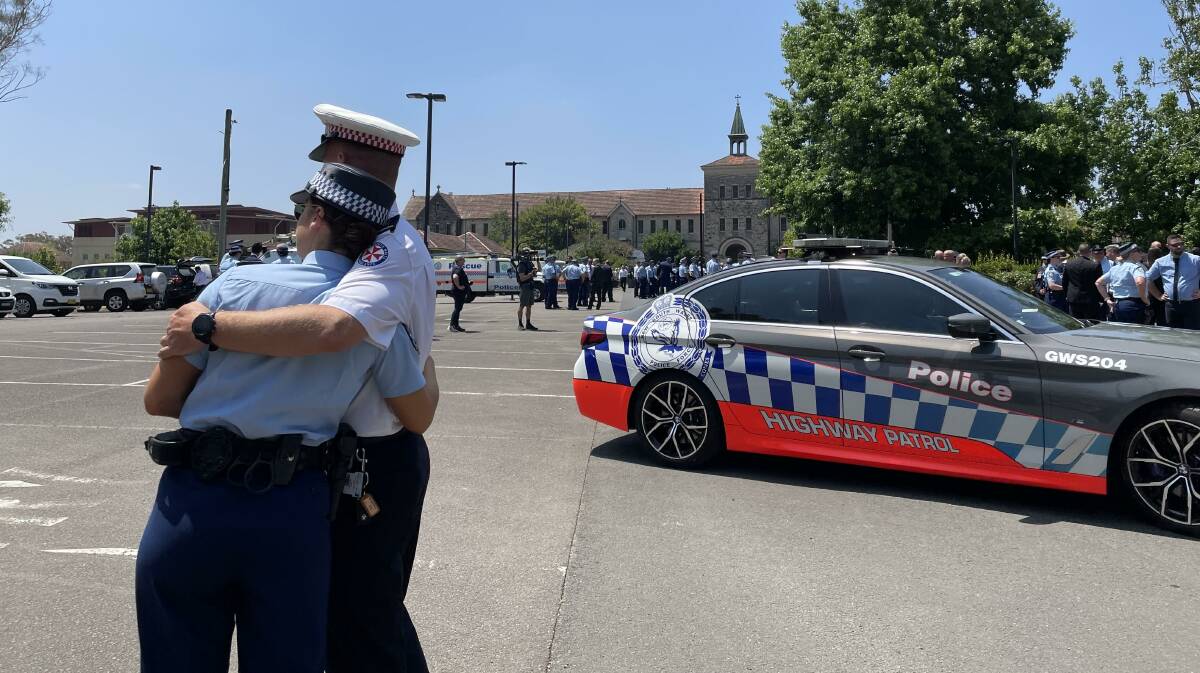 Emergency services officers embrace after the funeral service for Sergeant Peter Stone in Springwood. Picture by B C Lewis